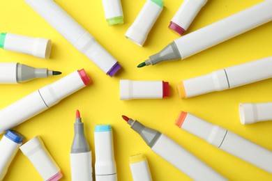 Photo of Colorful markers on yellow background, flat lay