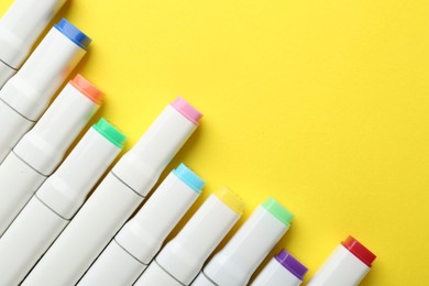 Colorful markers on yellow background, flat lay. Space for text