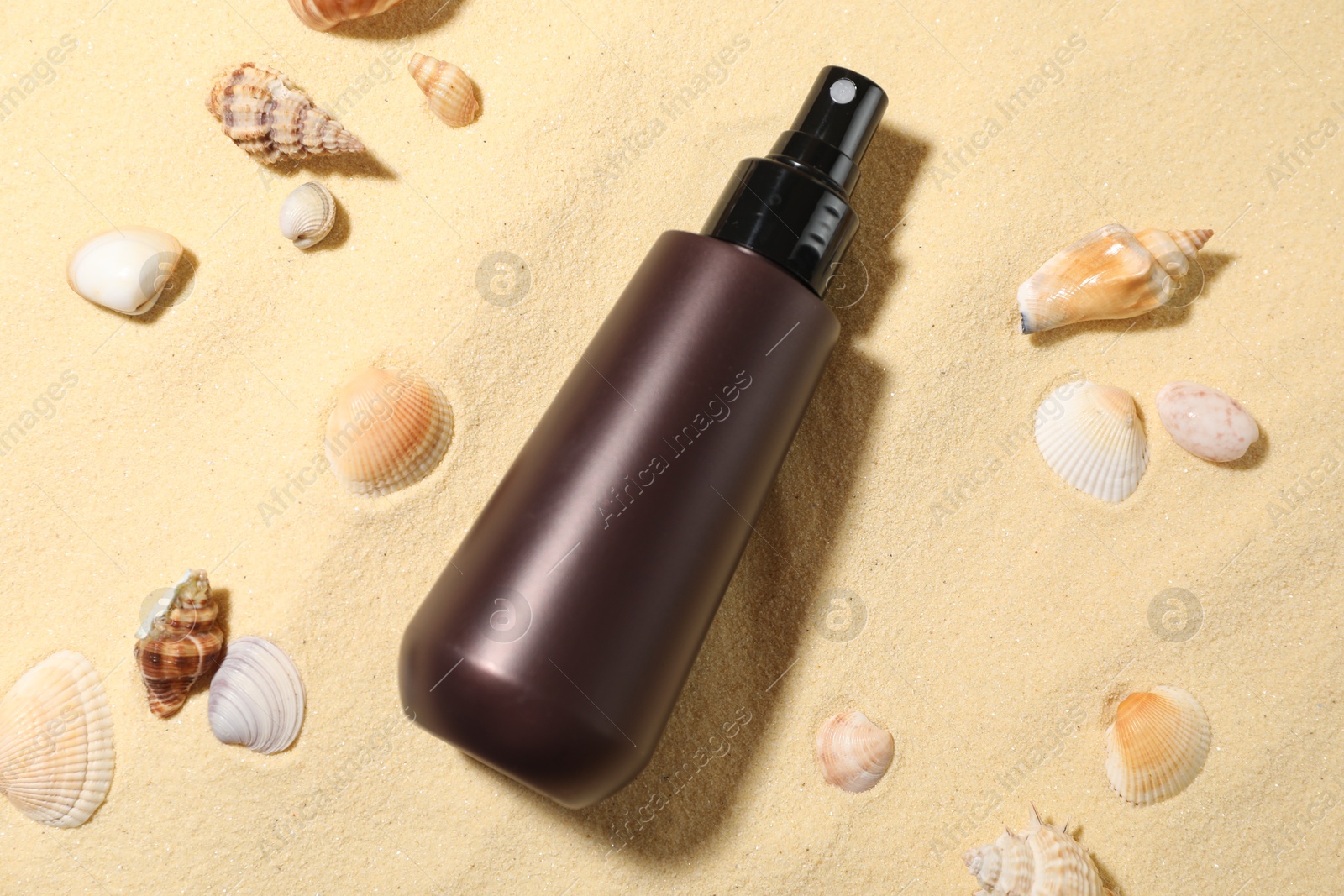 Bottle of sun protection product and seashells on sand, flat lay Photo of Bottle of sun protection product and seashells on sand, flat lay