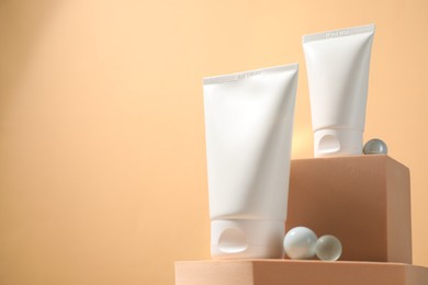 Tubes of sun protection product, decorative stones and podiums on beige background, space for text