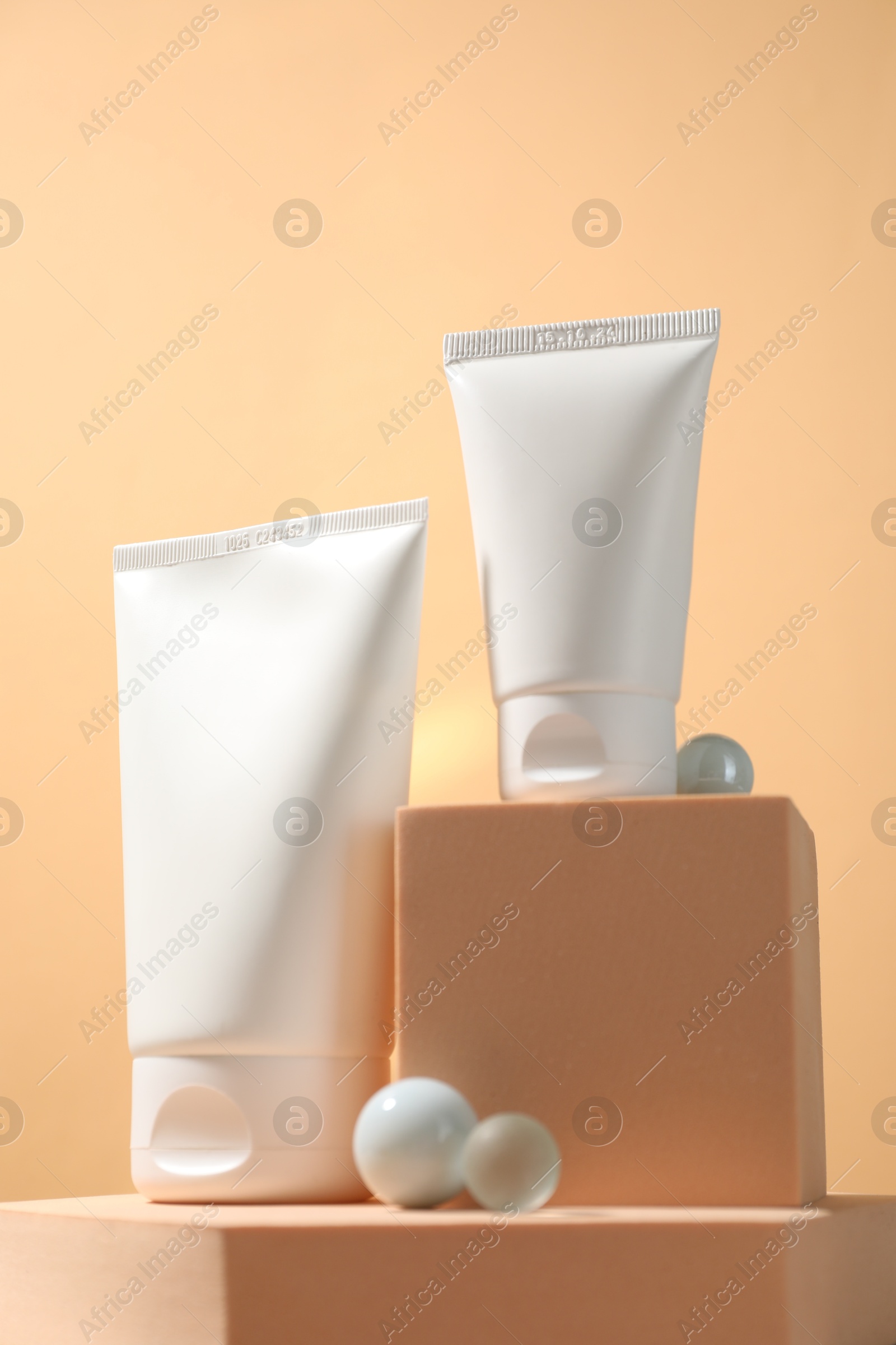 Photo of Tubes of sun protection product, stones and podiums on beige background