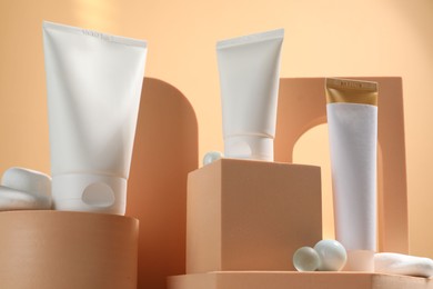 Tubes of sun protection product, decorative stones and podiums on beige background, low angle view