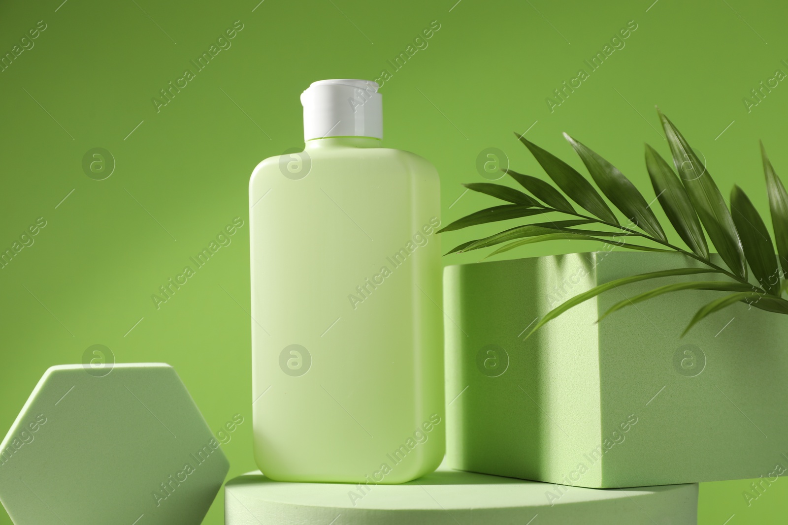 Photo of Bottle of sun protection product, branch and podiums against green background