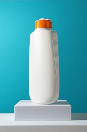 Bottle of sun protection product on podium against light blue background