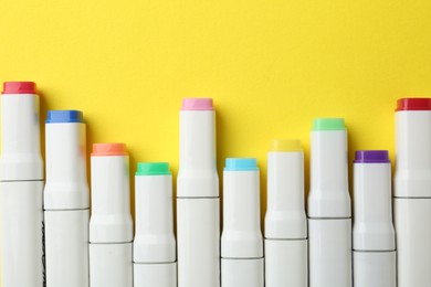 Colorful markers on yellow background, flat lay