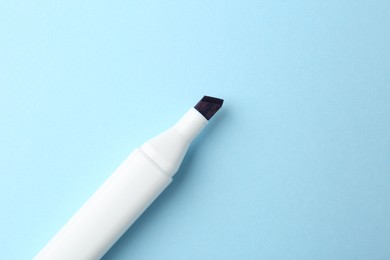 Photo of One color marker on light blue background, top view