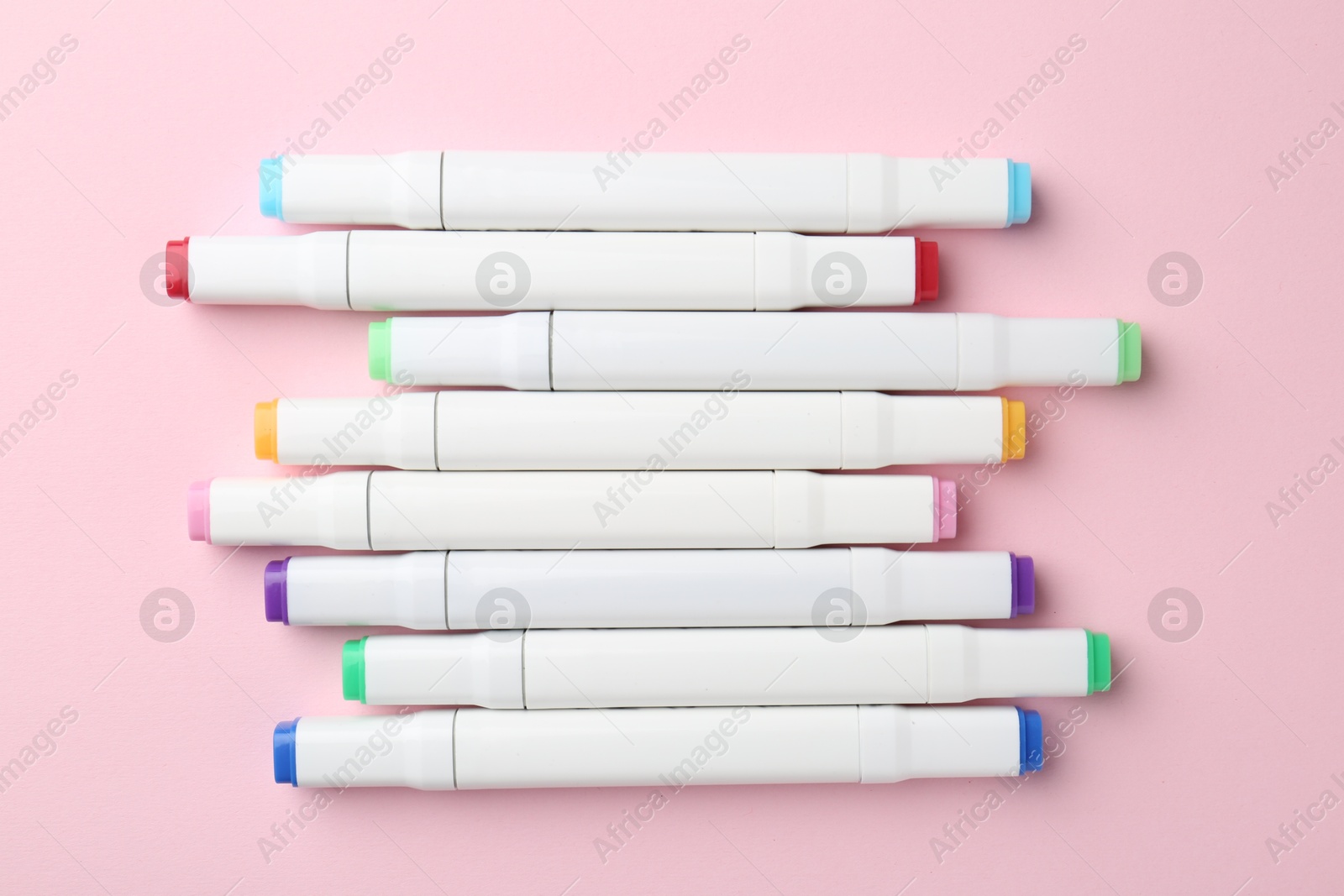 Photo of Colorful double sided markers on pink background, flat lay