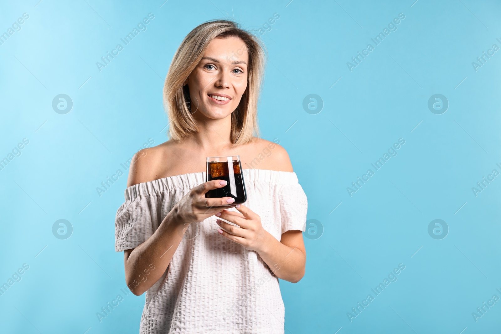 Photo of Woman with glass of refreshing soda drink on light blue background