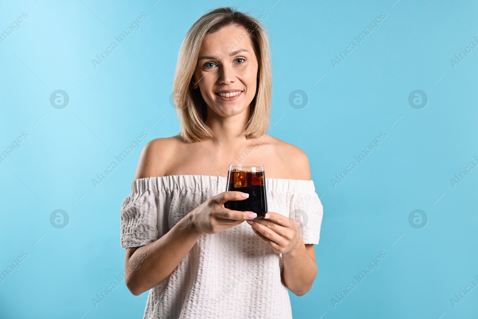 Photo of Woman with glass of refreshing soda drink on light blue background