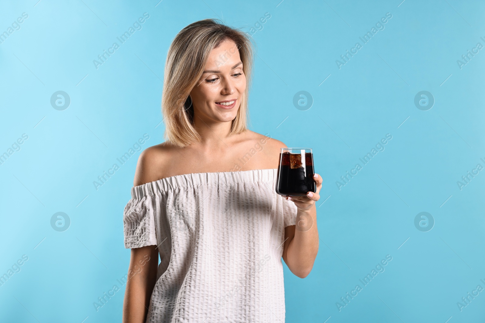 Photo of Woman with glass of refreshing soda drink on light blue background