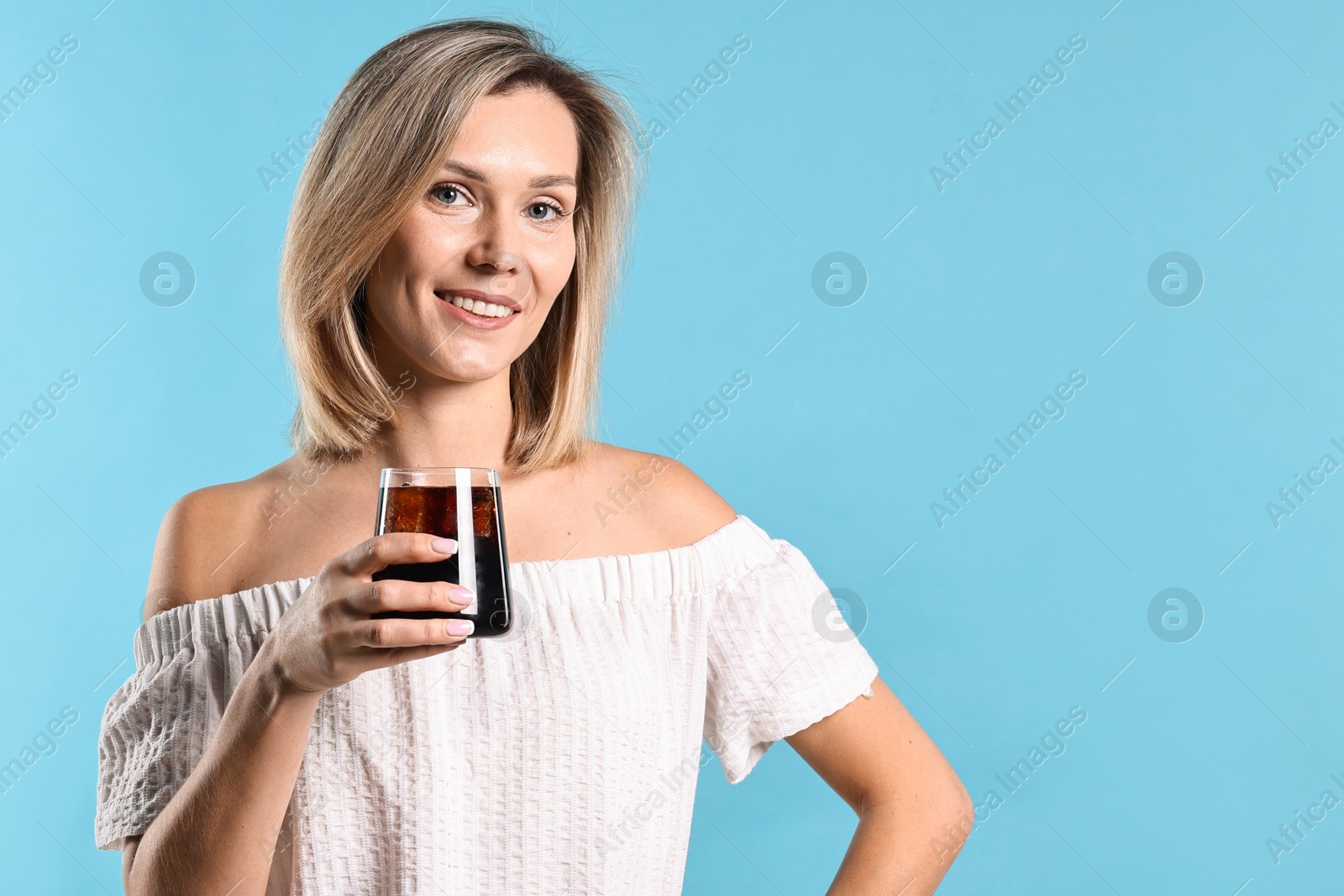 Photo of Woman with glass of refreshing soda drink on light blue background