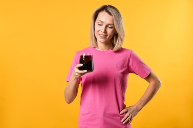 Photo of Woman with glass of refreshing soda drink on orange background