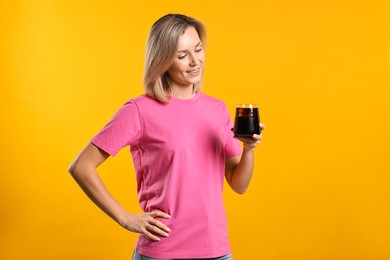 Photo of Woman with glass of refreshing soda drink on orange background