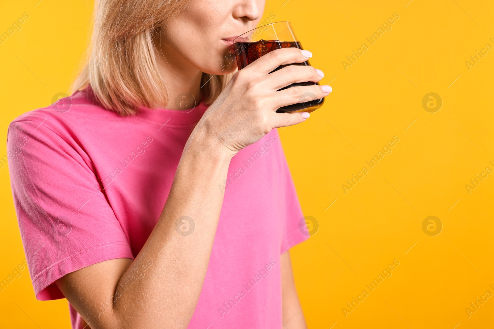 Photo of Woman drinking tasty refreshing soda drink on orange background, closeup. Space for text