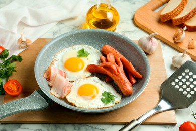 Photo of Tasty brunch. Fried eggs, sausages, bacon and spatula on white marble table, closeup