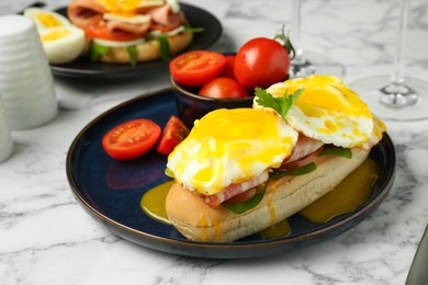 Photo of Tasty brunch. Poached eggs, bacon, bun and tomatoes on white marble table, closeup