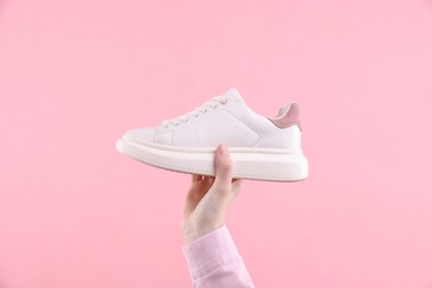 Woman with stylish sneaker on pink background, closeup