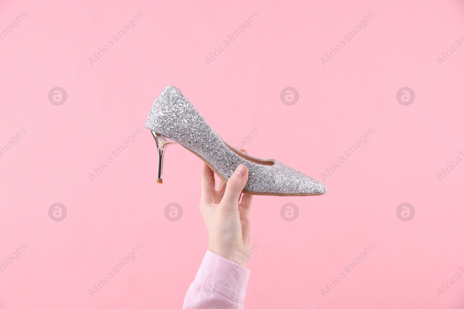 Photo of Woman with high heeled shoe on pink background, closeup