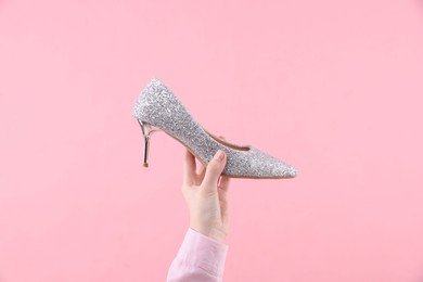 Woman with high heeled shoe on pink background, closeup