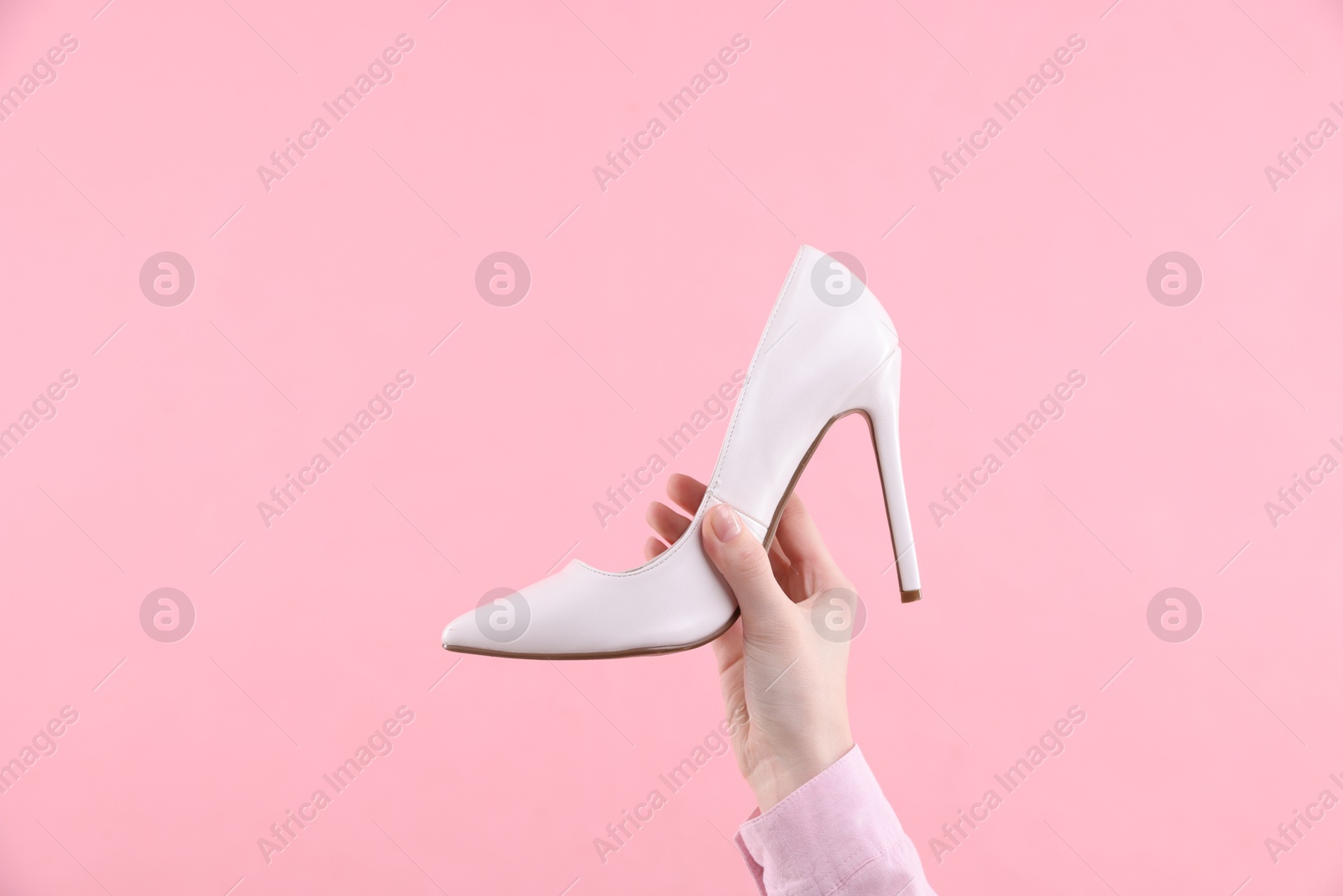 Photo of Woman with high heeled shoe on pink background, closeup