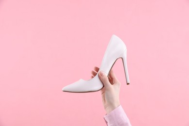 Woman with high heeled shoe on pink background, closeup