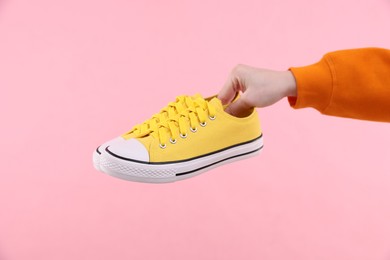 Photo of Woman with stylish sneakers on pink background, closeup