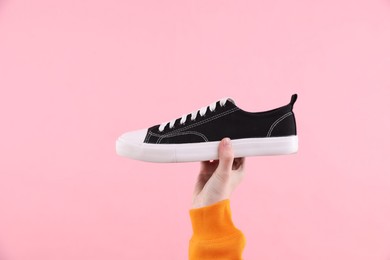 Woman with stylish sneaker on pink background, closeup