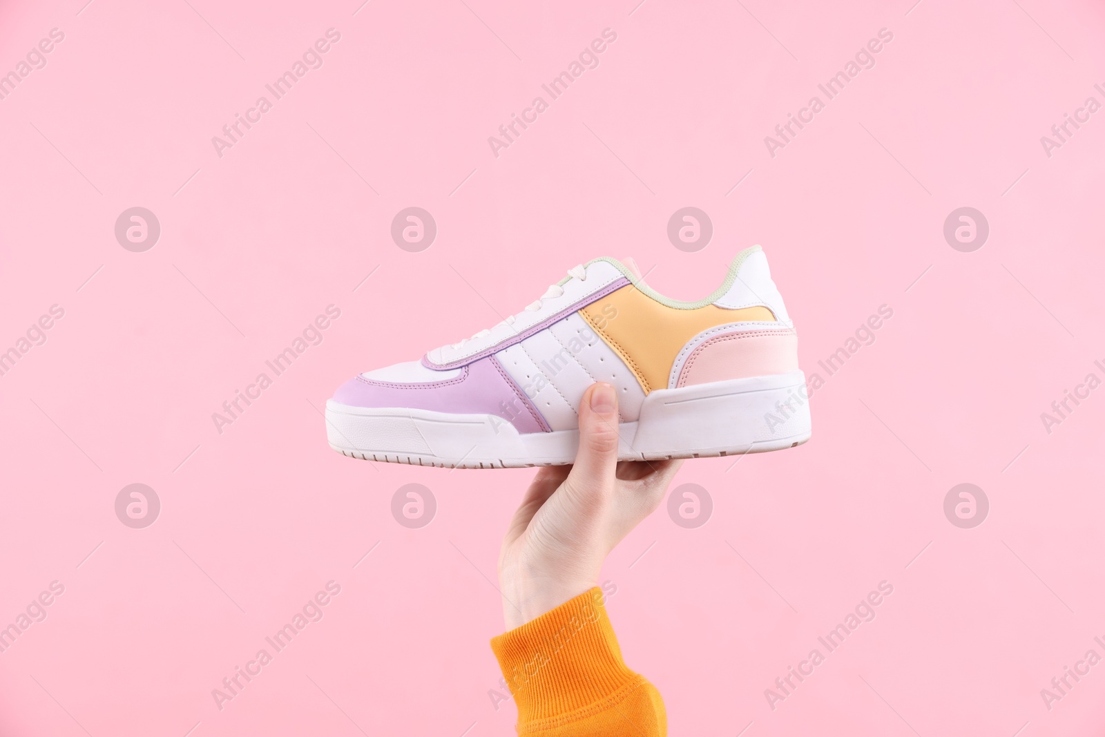 Photo of Woman with stylish sneaker on pink background, closeup