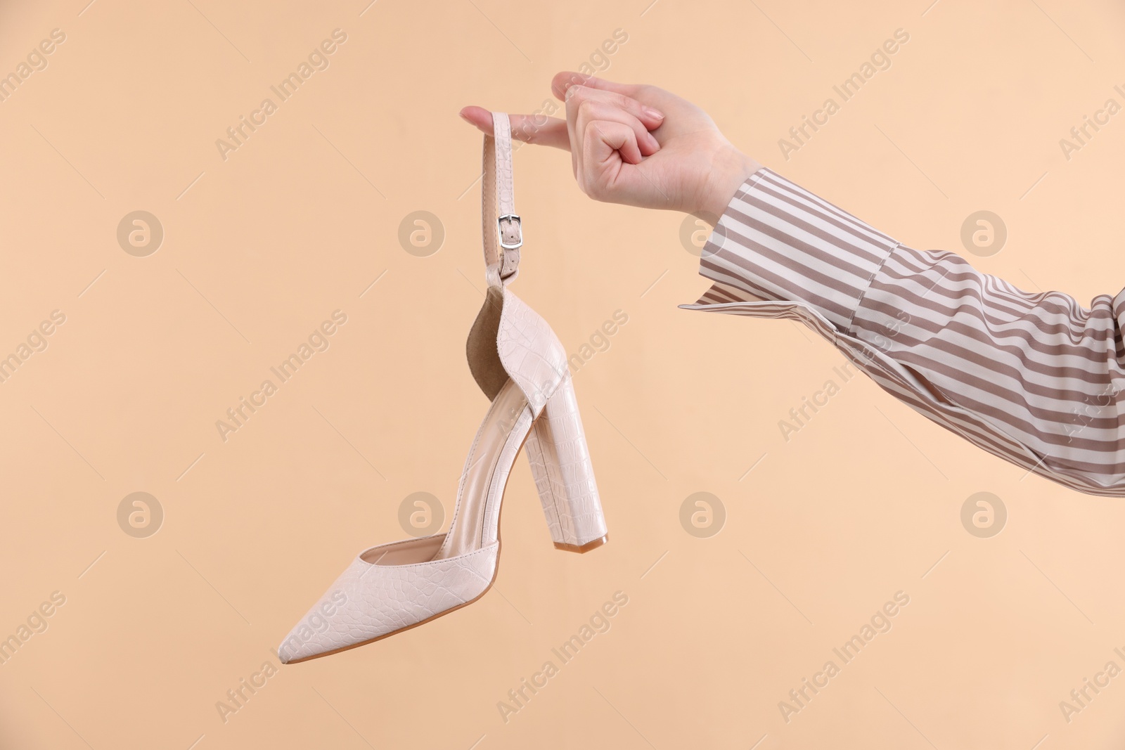 Photo of Woman with stylish shoe on beige background, closeup