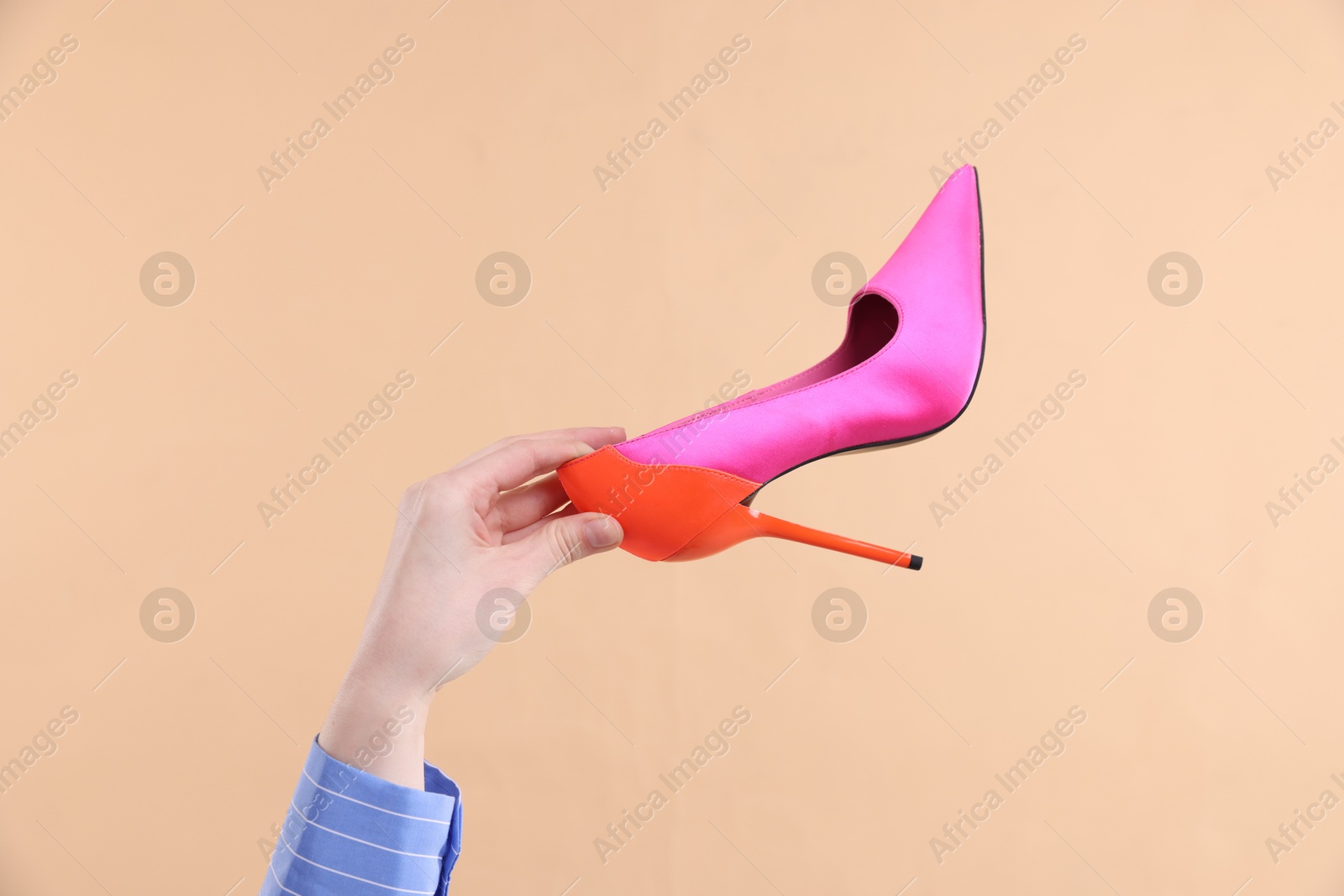 Photo of Woman with high heeled shoe on beige background, closeup