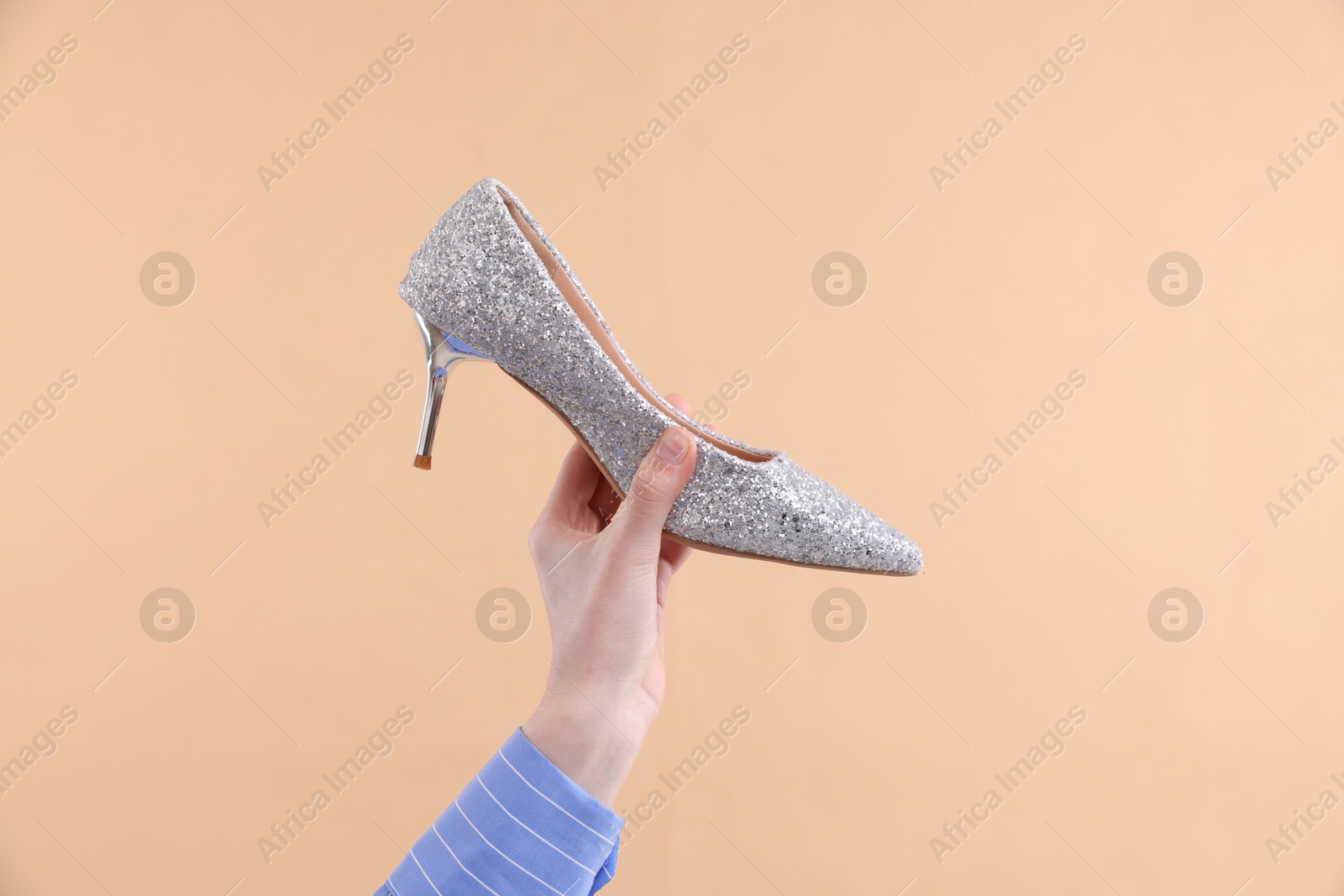 Photo of Woman with high heeled shoe on beige background, closeup