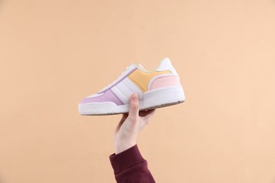 Photo of Woman with stylish sneaker on beige background, closeup