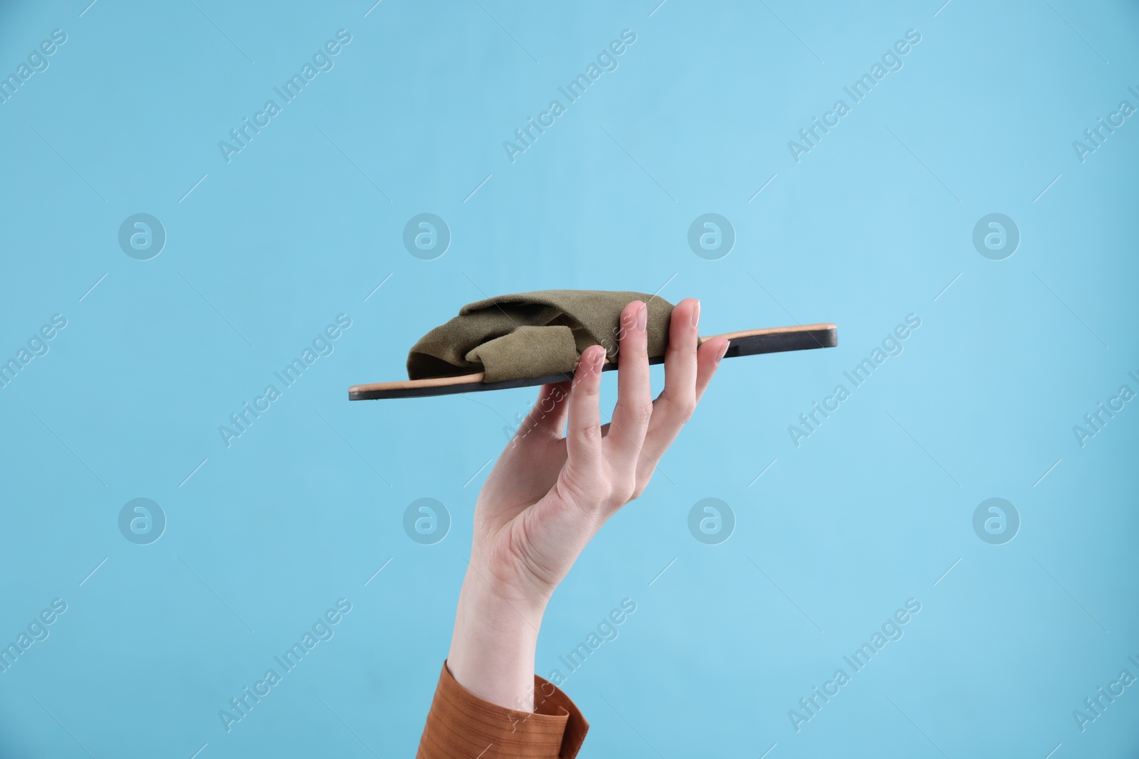 Photo of Woman with stylish slipper on light blue background, closeup