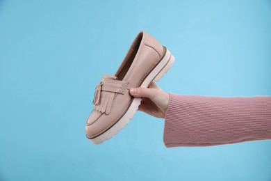 Woman with stylish shoe on light blue background, closeup