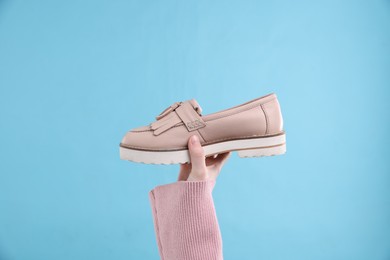 Photo of Woman with stylish shoe on light blue background, closeup