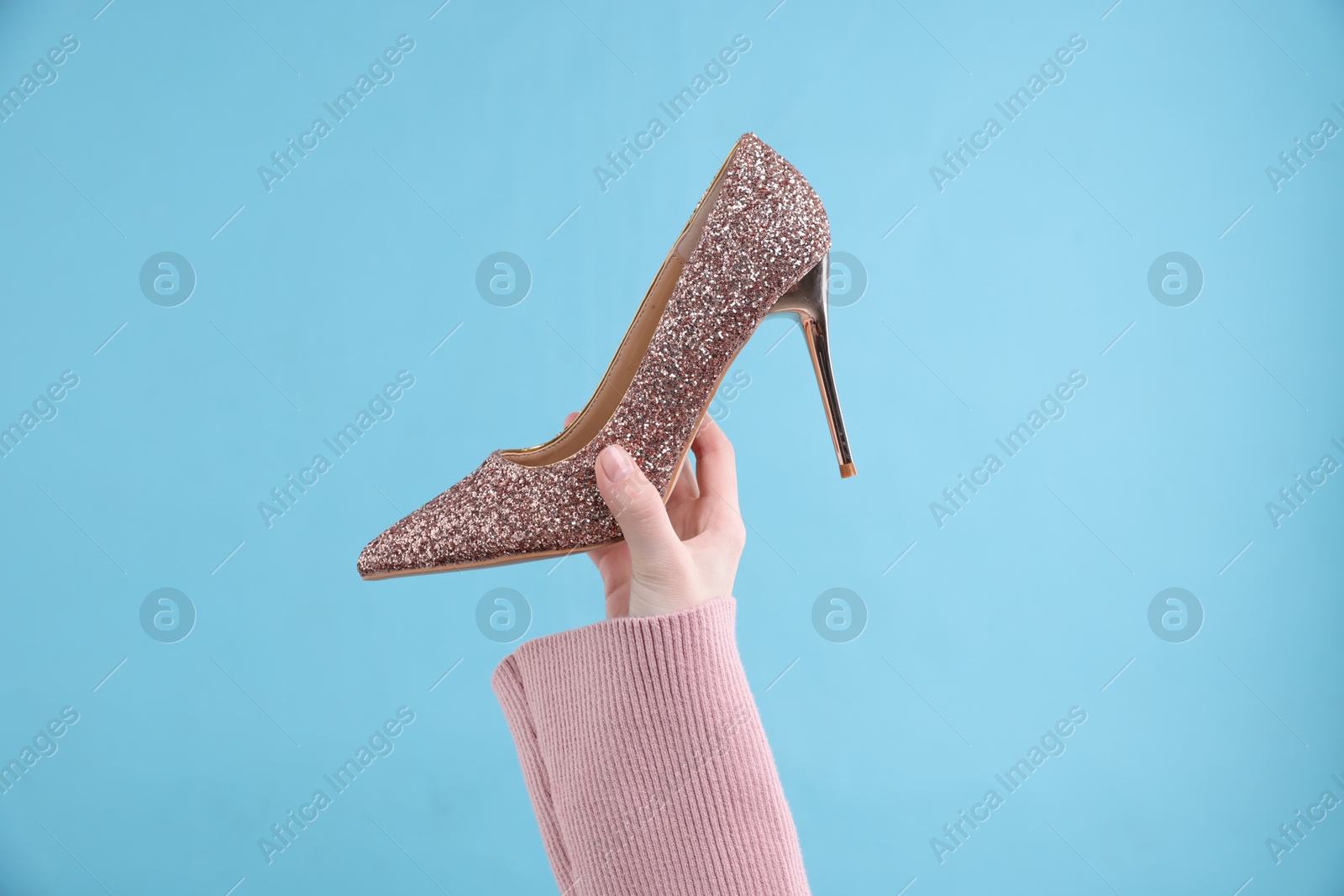 Photo of Woman with high heeled shoe on light blue background, closeup