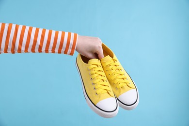 Photo of Woman with stylish sneakers on light blue background, closeup