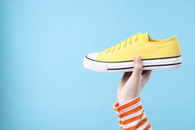 Photo of Woman with stylish sneaker on light blue background, closeup. Space for text