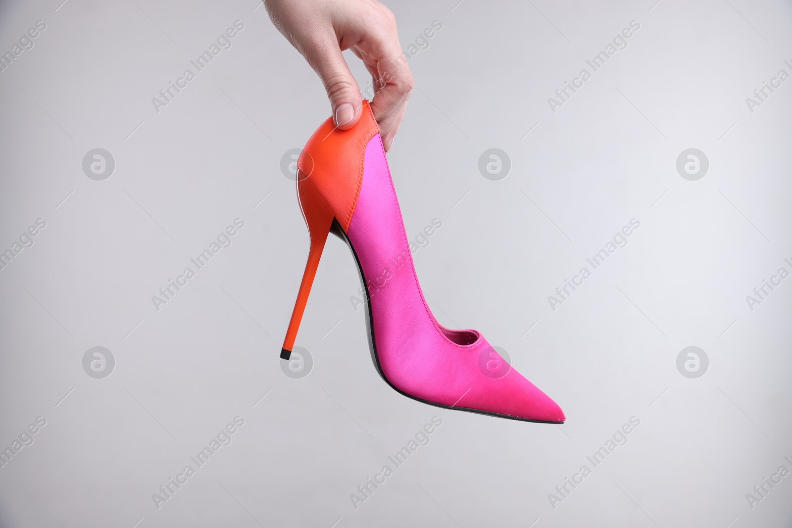 Photo of Woman with stylish high heeled shoe on grey background, closeup