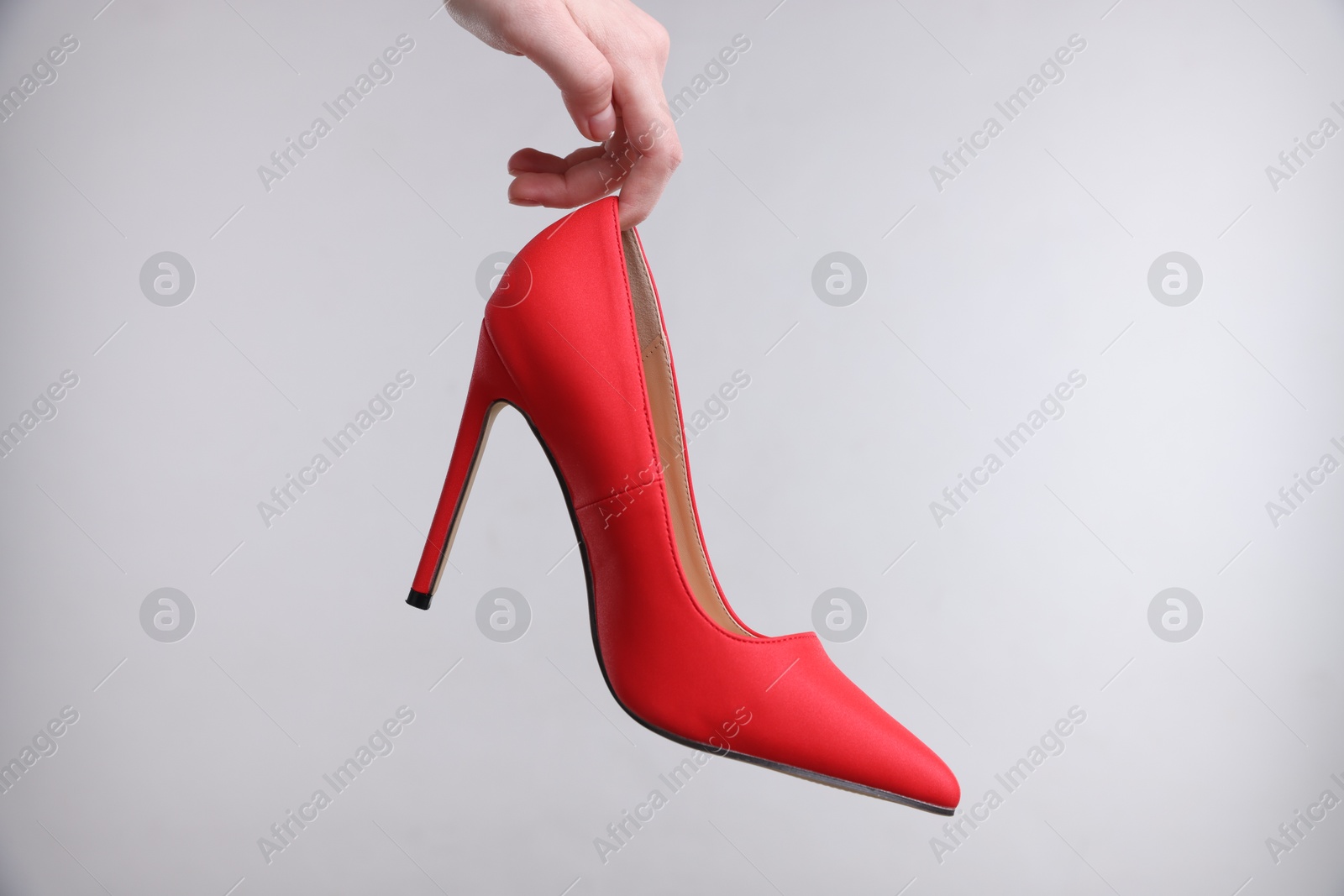 Photo of Woman with stylish high heeled shoe on grey background, closeup