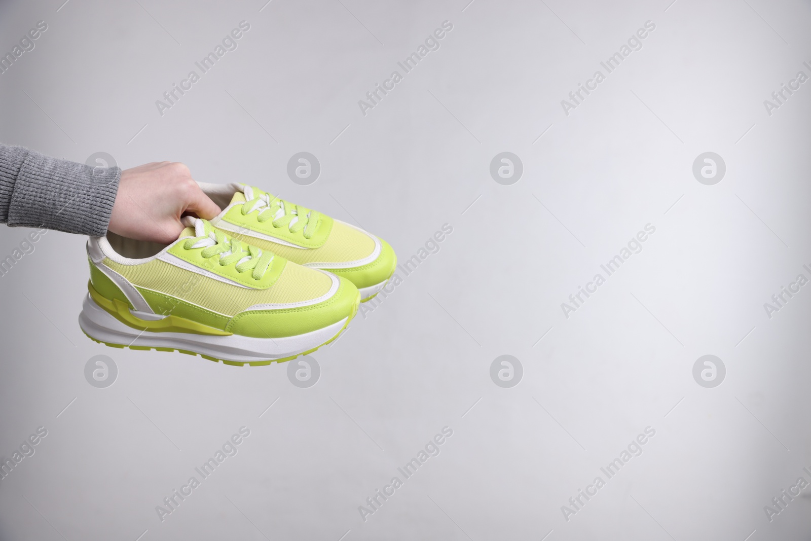 Photo of Woman with stylish sneakers on grey background, closeup. Space for text