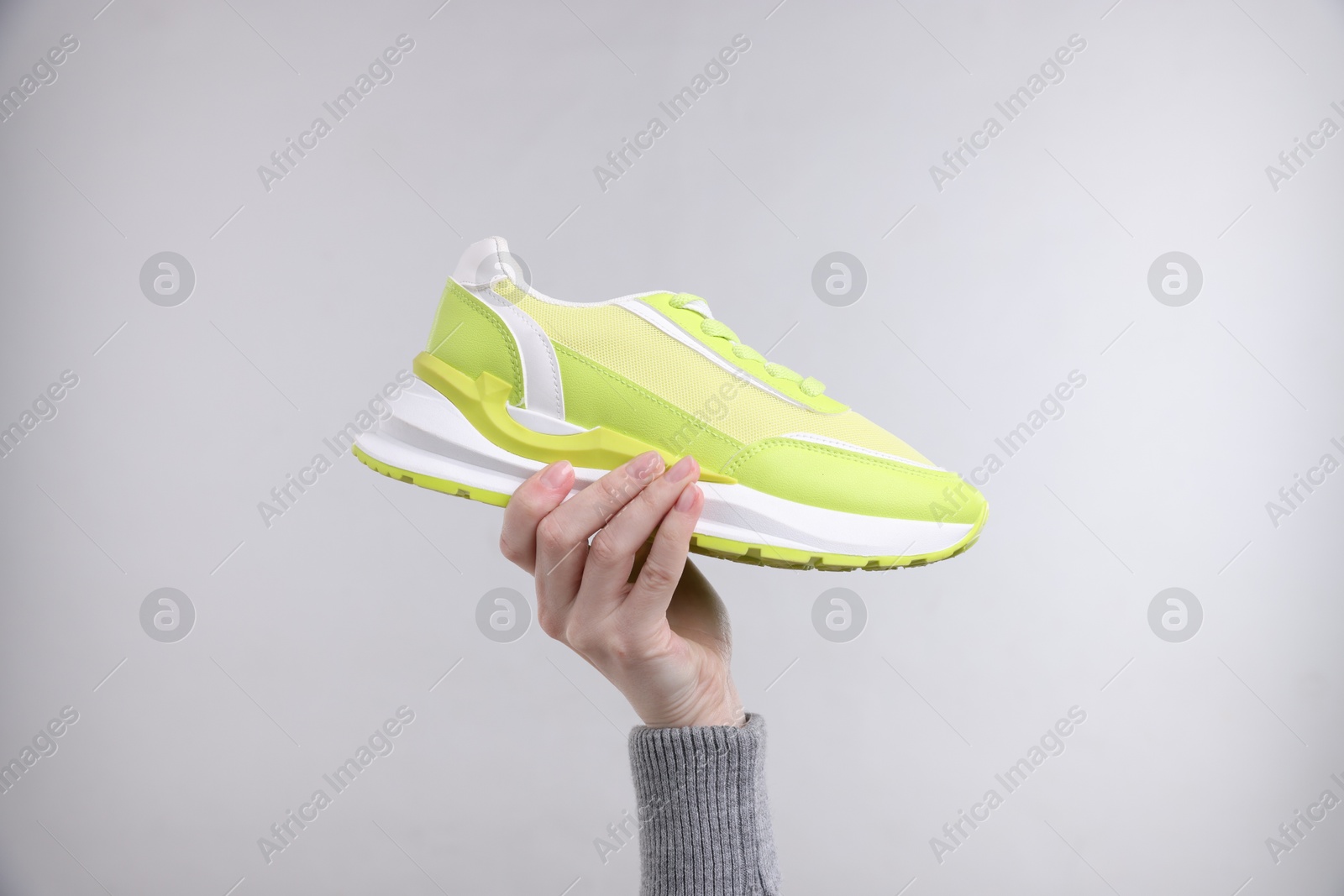 Photo of Woman with stylish sneaker on grey background, closeup