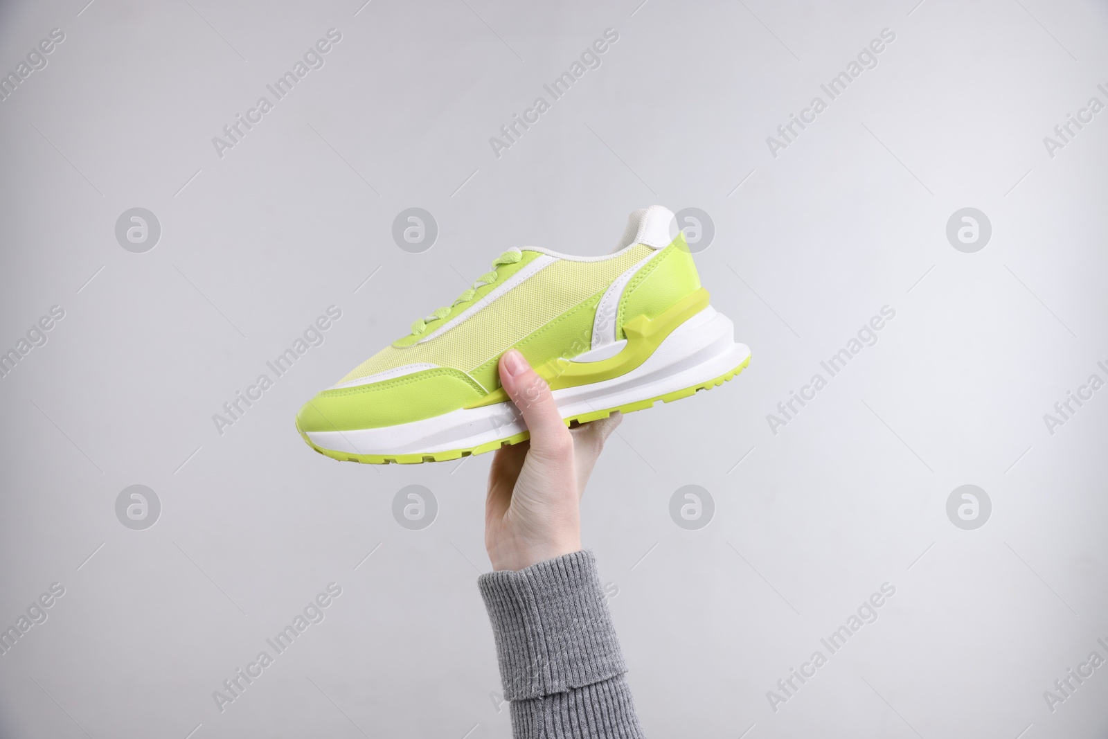 Photo of Woman with stylish sneaker on grey background, closeup