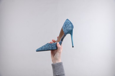 Woman with stylish high heeled shoe on grey background, closeup