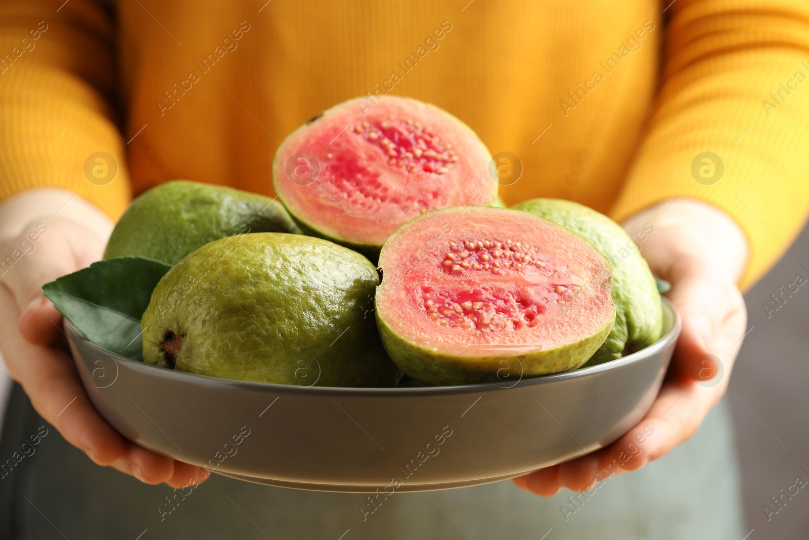 Photo of Woman with bowl of fresh guava fruits, closeup