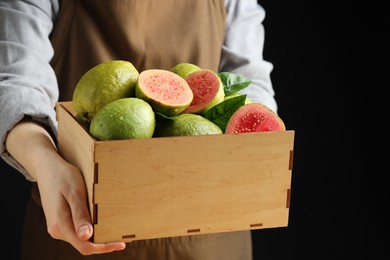 Photo of Woman with fresh guava fruits on black background, closeup