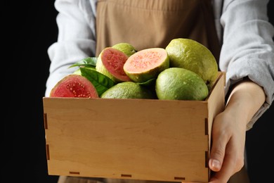 Photo of Woman with fresh guava fruits on black background, closeup