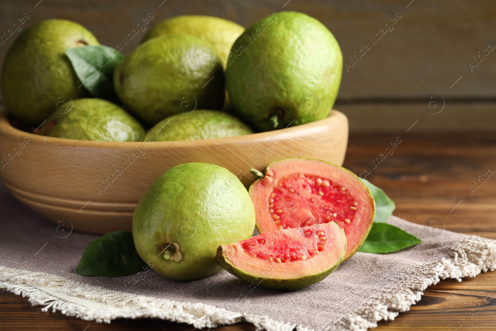 Photo of Fresh cut and whole guava fruits on wooden table, closeup