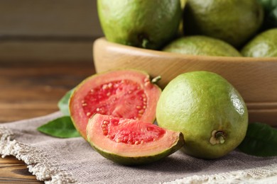 Fresh cut and whole guava fruits on wooden table, closeup