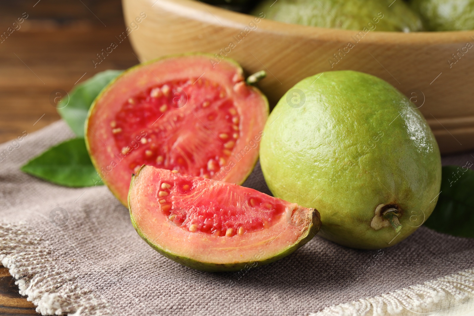 Photo of Fresh cut and whole guava fruits on table, closeup